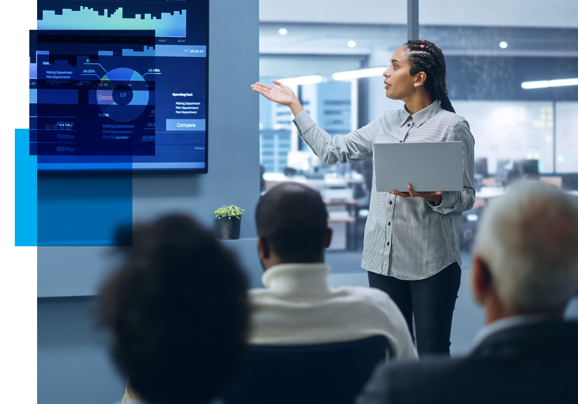 Image of a woman at the head of a conference room pointing at a slide of analytics with an audience watching in the foreground. Related to: database administrator job, business analyst job, data engineer job, data services job, service now business analyst remote job, remote service now analyst, senior program analyst job, sr program analyst career, network engineer job, network engineer position, agile environment, data scientist job, data consumer job,