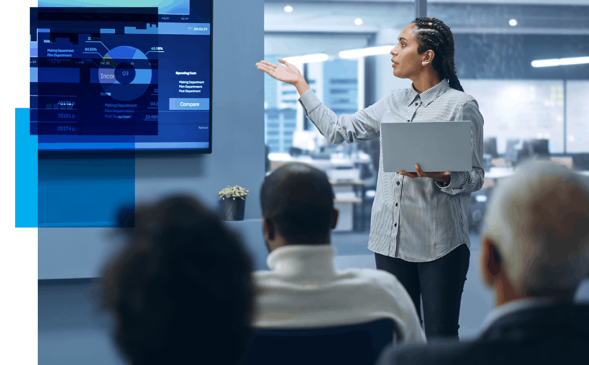 Image of a woman at the head of a conference room pointing at a slide of analytics with an audience watching in the foreground. Related to: database administrator job, business analyst job, data engineer job, data services job, service now business analyst remote job, remote service now analyst, senior program analyst job, sr program analyst career, network engineer job, network engineer position, agile environment, data scientist job, data consumer job,