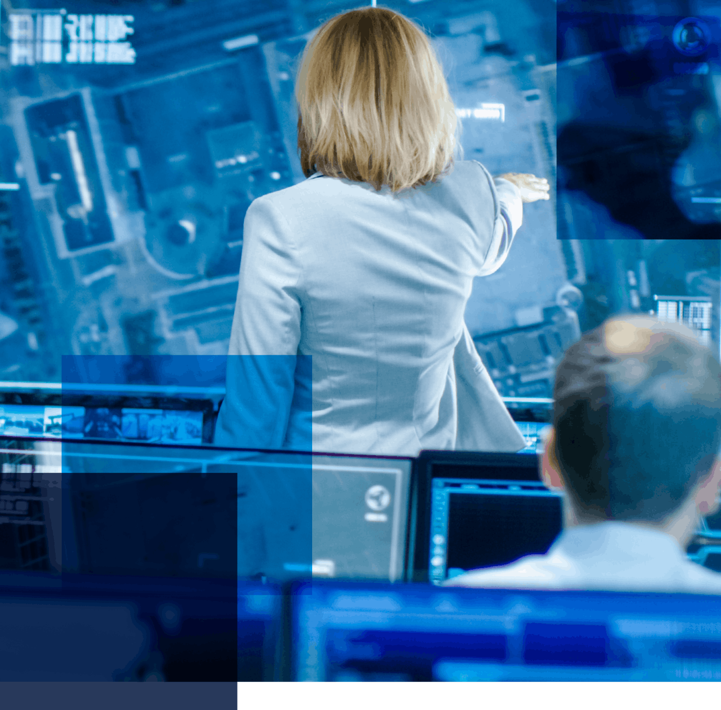 Image featuring a woman with her back to us, directing someone and standing among a bank of computers with a man in the fore ground looking at his computer screen. Related to: U.S. Special Operations Command (SOCOM), full digital support services, socom infrastructure modernization, agile cloud operating model, automated infrastructure, dynamic information network communications