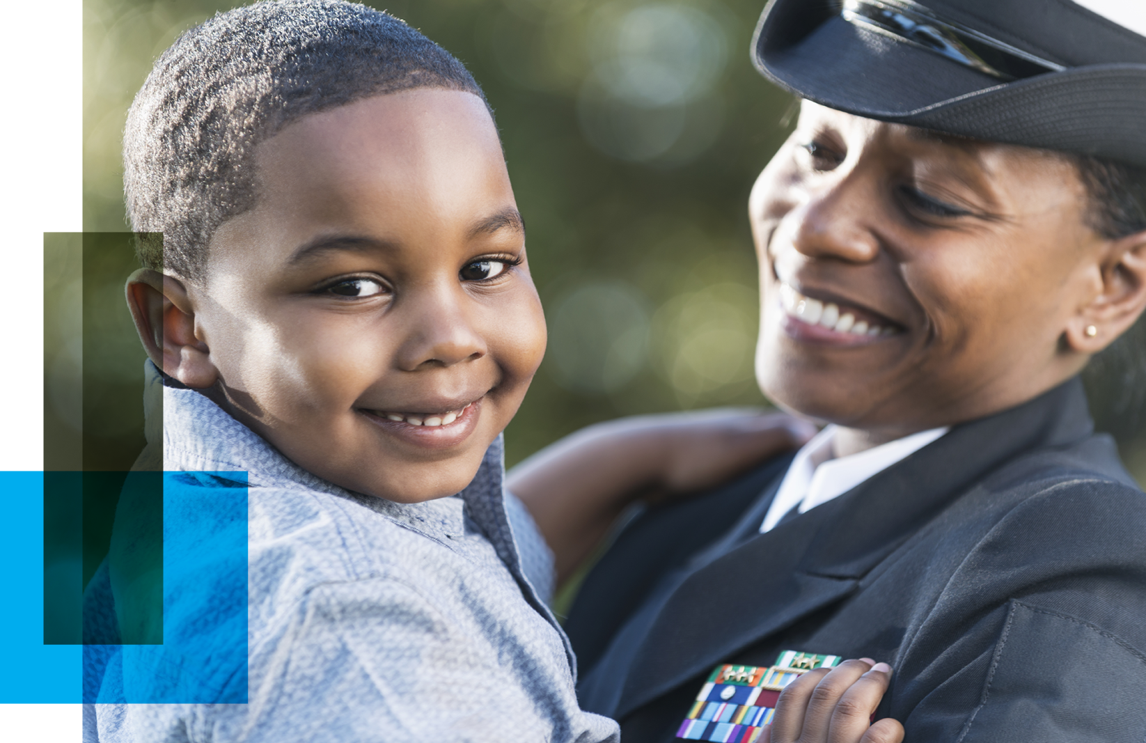 Image shows a black woman in naval uniform holding her child and smiling. The boy looks at the camera, also smiling.