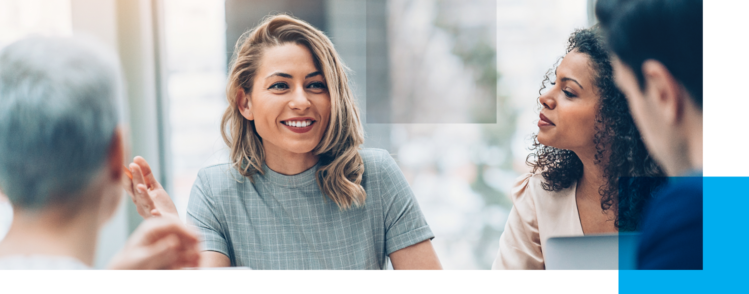 Image shows four people in a group with a woman facing the camera while the others are turned towards her.