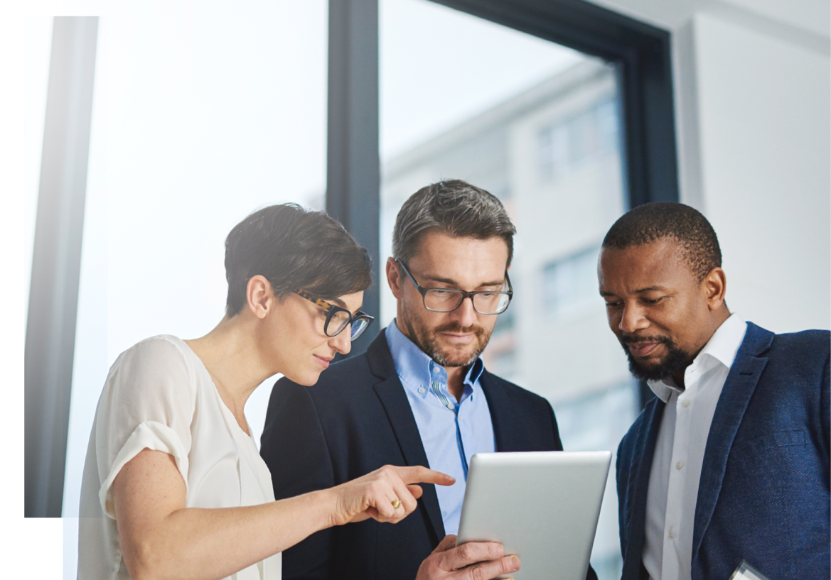 Image of two men and a woman conferring over a tablet with the woman pointing out something on the screen.