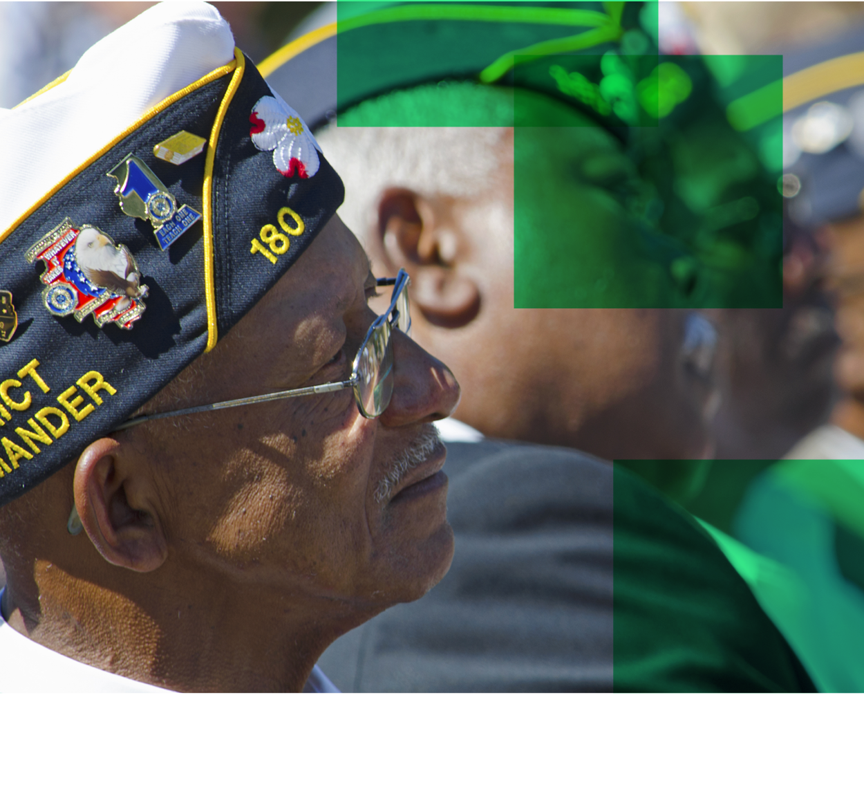 Older African American veterans with navel hats on sit in a row staring towards the right edge of the image.