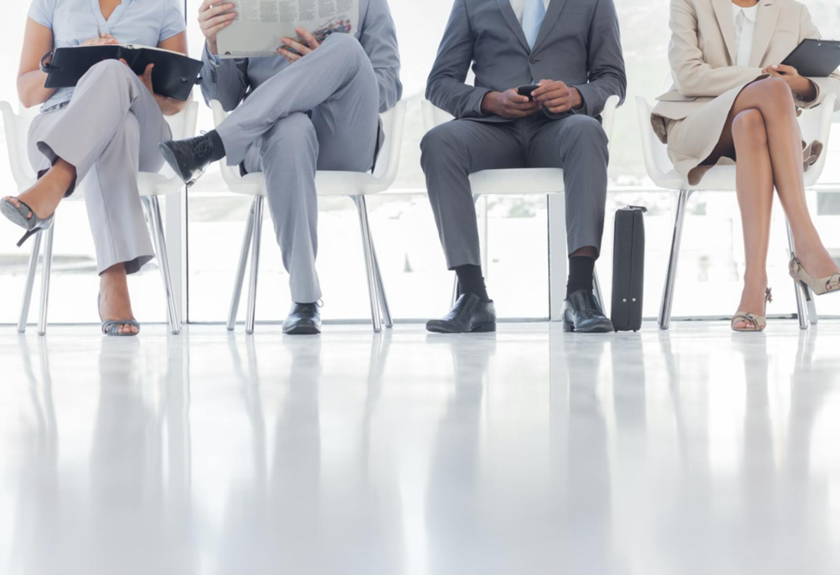 Image shows legs of four people sitting in a row. Related to VA HR modernization plan, hr modernization, human resources and AI, human resources digital tools, cyber workforce.