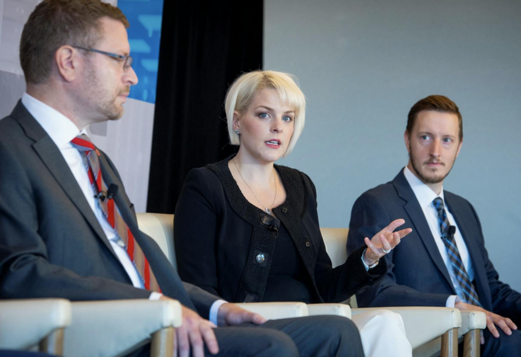 Image of a woman talking and sitting between two men. Related to: Modernized Cloud Infrastructure, Advanced Data Capabilities, agencies and ai automation, data analytics projects, hybrid cloud tools.
