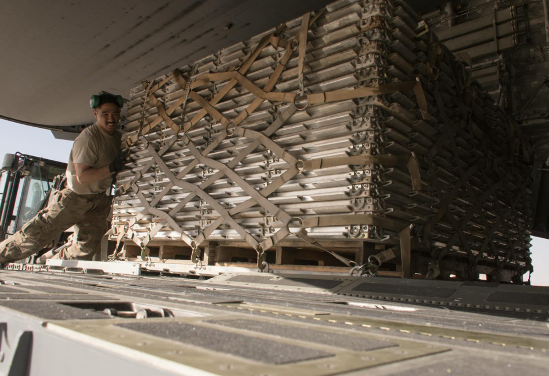 Soldier in fatigues pushing a pallet of strapped goods up a plan's ramp. Cyber Supply Chain Risks, cyber logistics, supply chain, supply chain security, cyber supply chain risk assessment, cyber supply chain management.