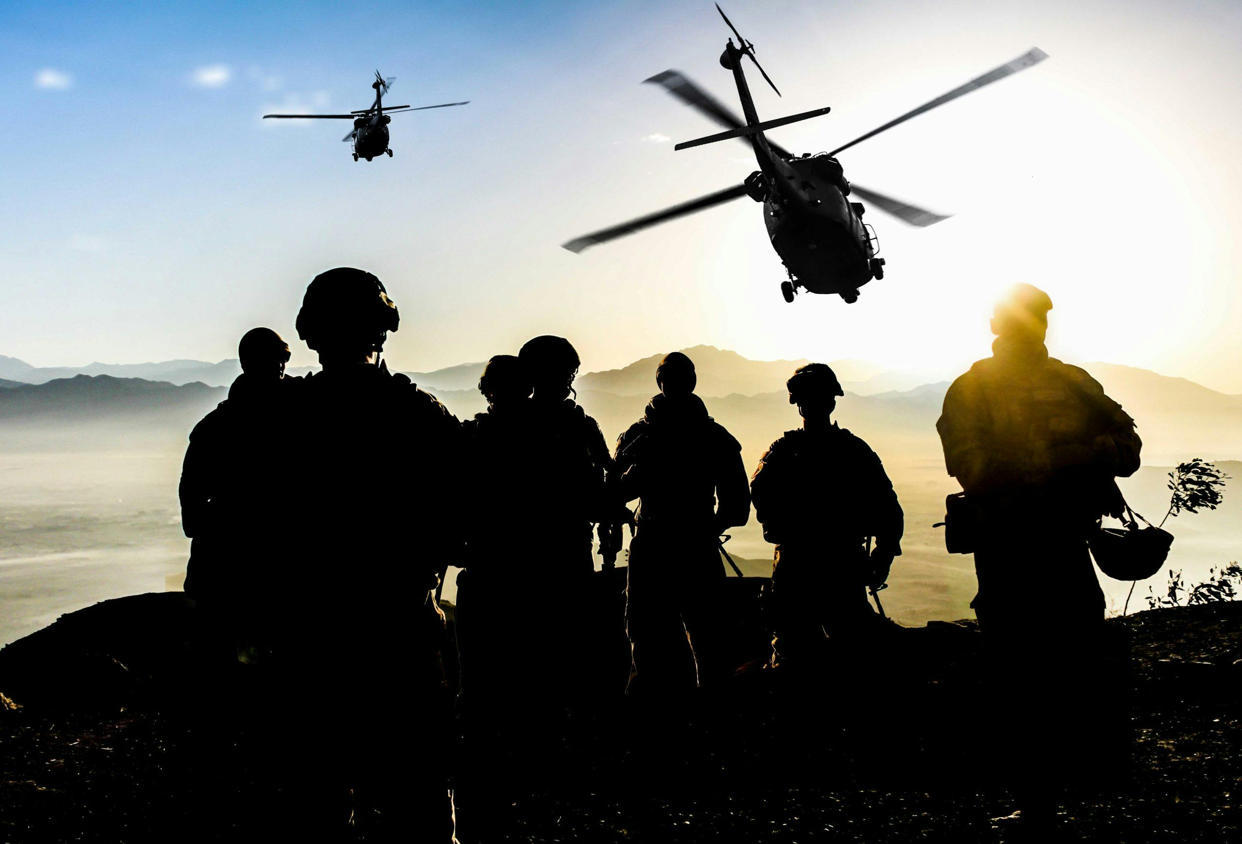 Image showing silhouettes of soldiers atop a mountain with the sun in the background and two helicopters flying in towards them. Related to: deployable communications kits, scalable communications kits, DOD compliance, warfighter communications kits, remote connectivity, deployed warfighters connectivity