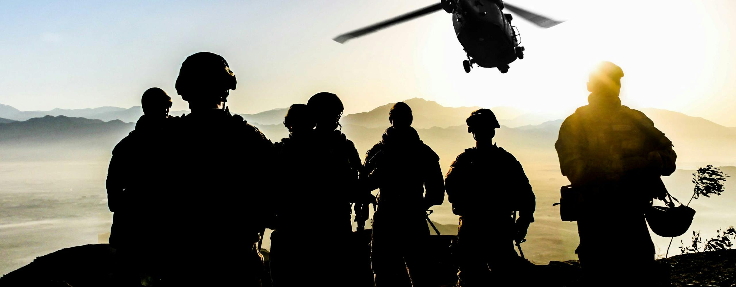 Image showing silhouettes of soldiers atop a mountain with the sun in the background and two helicopters flying in towards them. Related to: deployable communications kits, scalable communications kits, DOD compliance, warfighter communications kits, remote connectivity, deployed warfighters connectivity