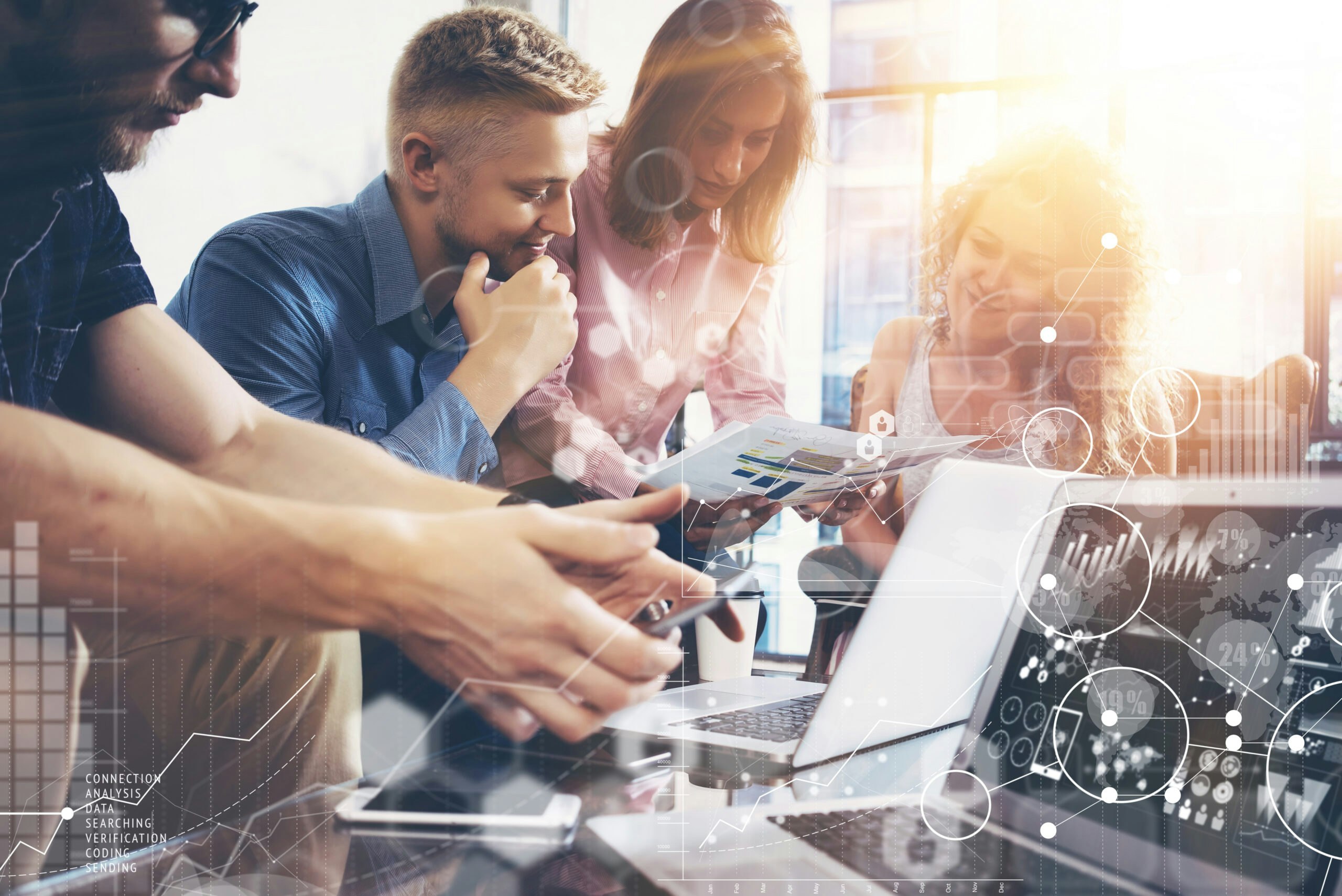 Image shows people conferring over paper plans with laptops on a table in front and transparent illustrations of analytic graphs overlaid on top. Related to: agile transformation, va agile modernization, agile and SAFe, continuous improvement, oit, office of information and technology.