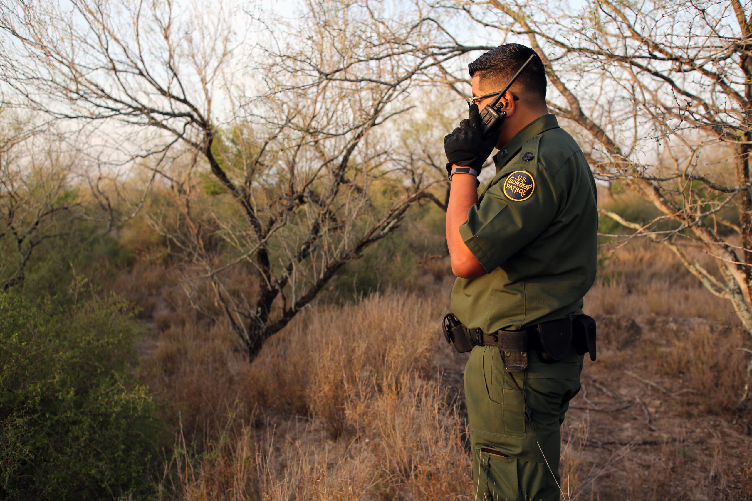 A Border Patrol agent talks on his radio at dawn while searching for a group of six people who illegally crossed the Rio Grande River from Mexico to enter the U.S.