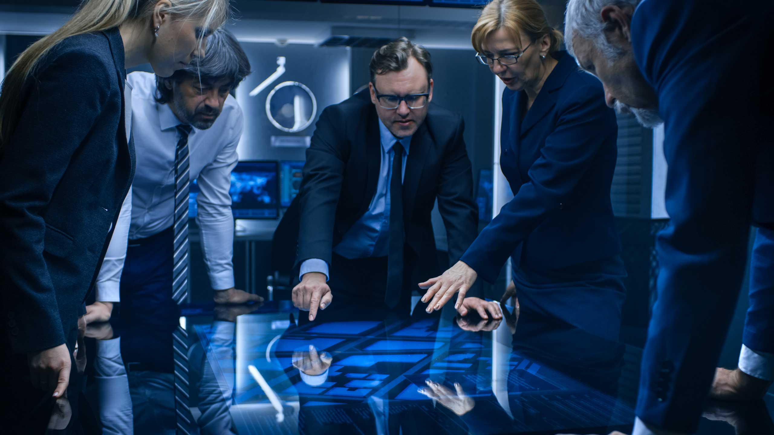 Businessmen standing around a glowing blue CRT table