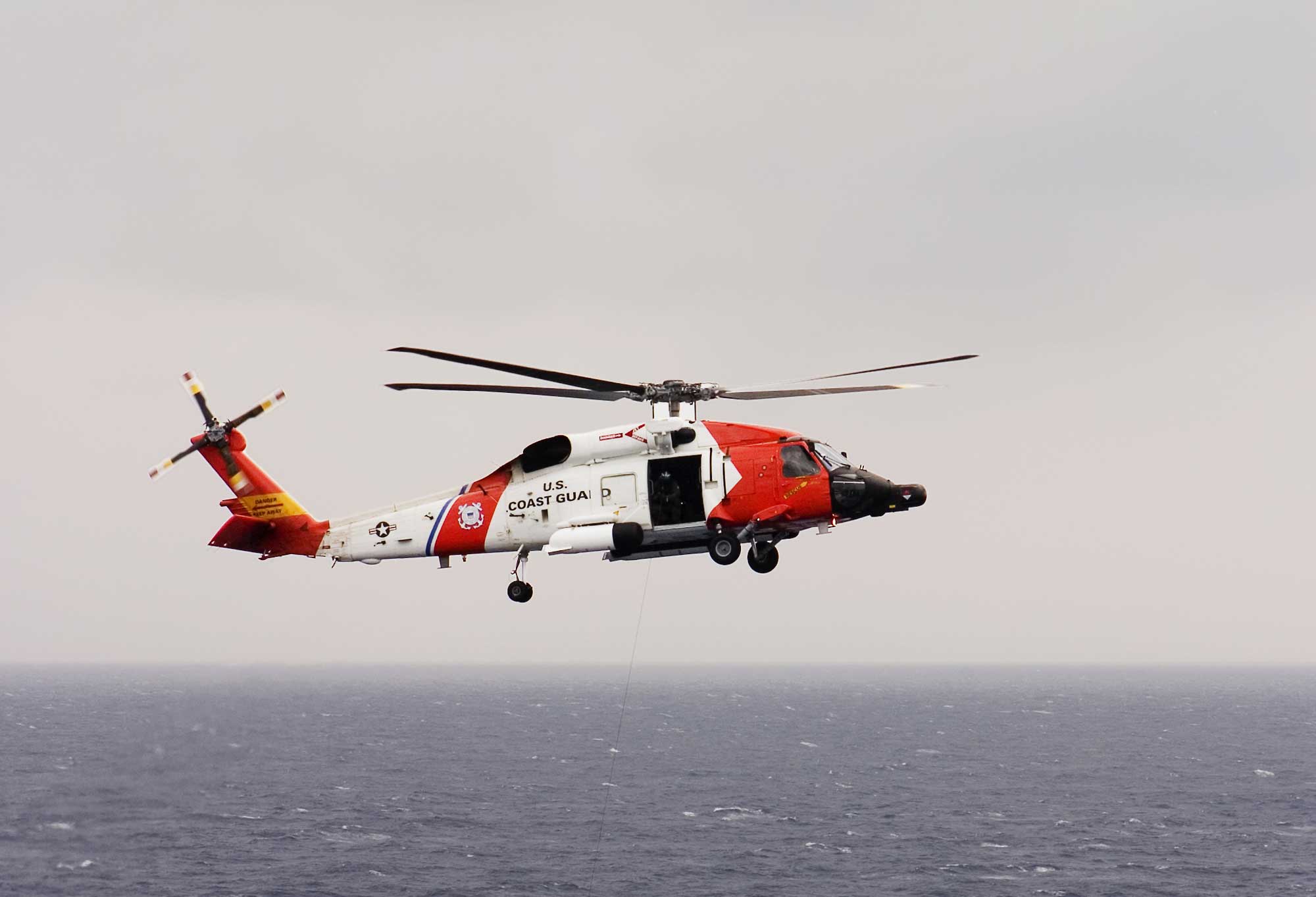 A Coast Guard helicopter in flight over the ocean